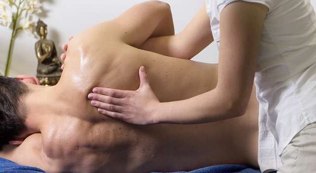 Ein Mitarbeiter eines Unternehmens erhält eine betriebliche Massage - hier wird gerade sein rechtes Schulterblatt massiert Ein Mitarbeiter eines Unternehmens erhält eine betriebliche Massage - hier wird gerade sein rechtes Schulterblatt massiert
